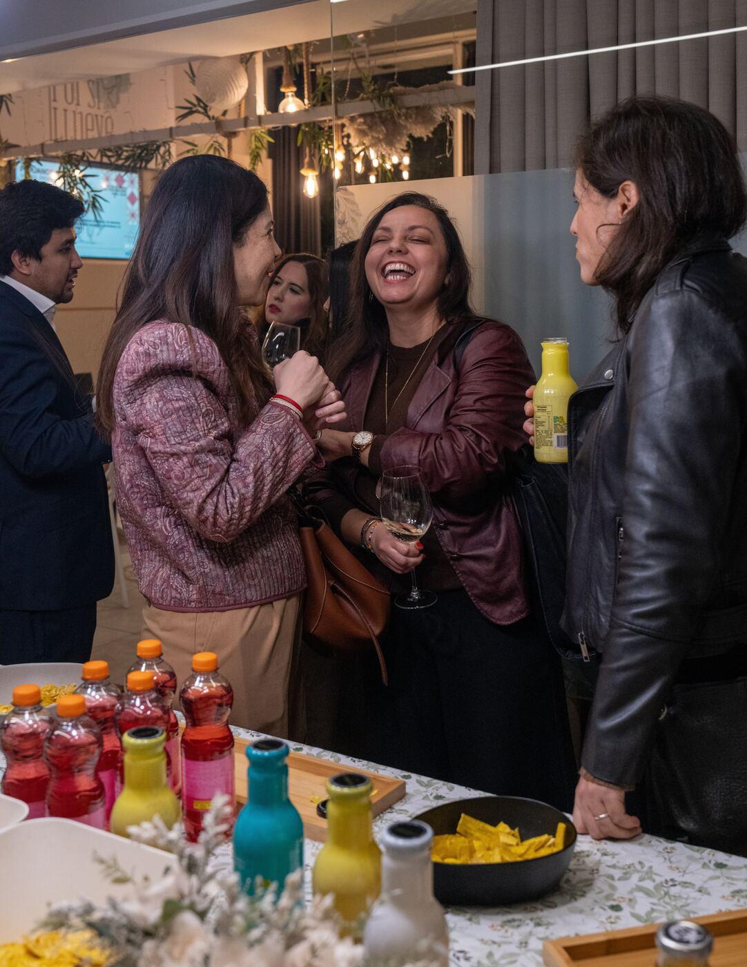 Tres asistentes se ríen con una copa en la mano en el encuentro de peruanos en Madrid