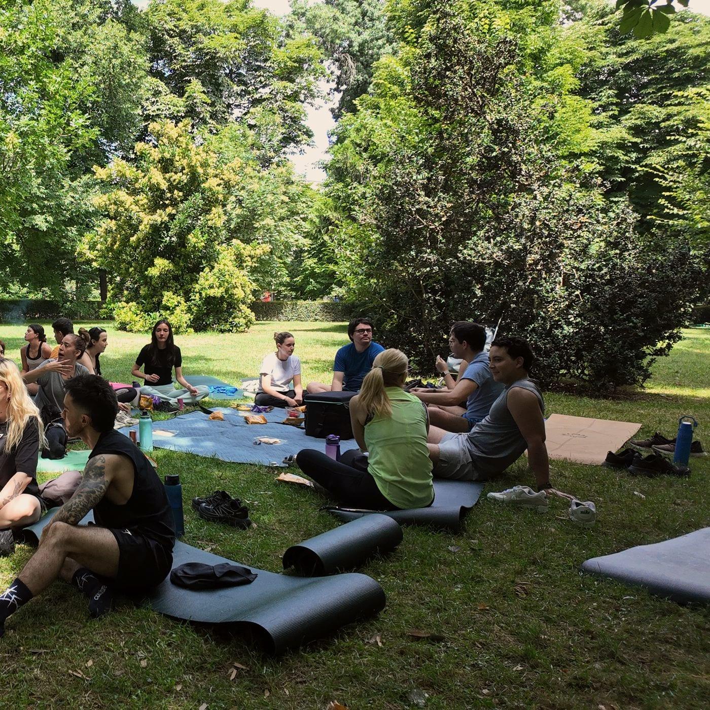 Un grupo de migrantes hispanos sentado en corro sobre el césped, conversando en un parque de Madrid